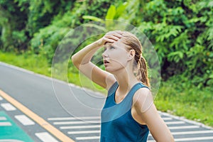 Tired runner sweating after running hard in countryside road. Exhausted sweaty woman after marathon training on hot