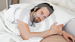 Tired sad depressed millennial caucasian man with stubble cant fall asleep in white bed, suffer from health problems