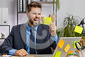Tired sad exhausted businessman working on laptop at office with many sticker tasks, panic attack