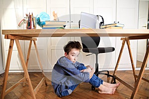 Tired sad frustrated boy sitting at the table with many books. Learning difficulties, school, education, online learning at home