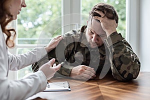 Tired and sad soldier with war syndrome during therapy with psychotherapist