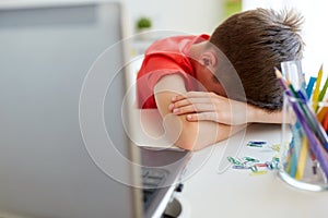 Tired or sad student boy with laptop at home