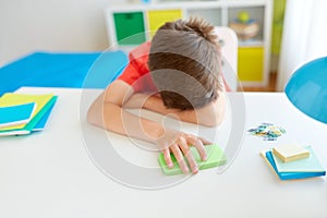 Tired or sad student boy with smartphone at home