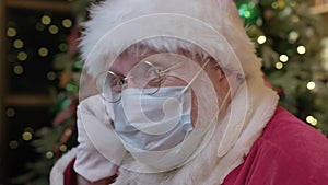 Tired Santa Claus removes medical mask from his face and exhales air from his lungs with relief. Freedom from