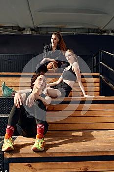 Tired satisfied girls and a guy after playing ball on the city playground. Diversity men and women playing basketball