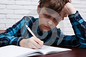 Tired schoolboy falling asleep while studying at copybook. Study