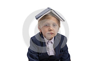 Tired schoolboy is isolated on white background. Portrait of boy in jacket or school uniform with book on his head