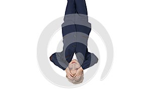 Tired schoolboy put hands on forehead. Portrait of boy in school uniform upside down. Isolated on white background