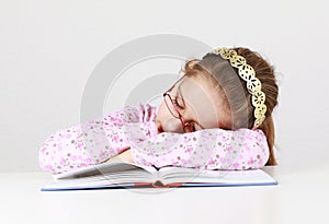 Tired schoolgirl sleeping on book