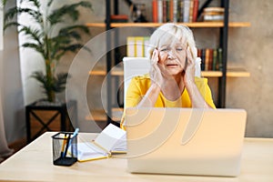 Tired senior business woman is using laptop