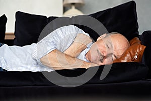Tired senior hispanic man sleeping on couch, taking afternoon nap