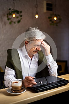 Tired senior man with laptop in the bar