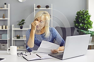 Tired senior woman receiving bankruptcy notification or rejection letter and crying