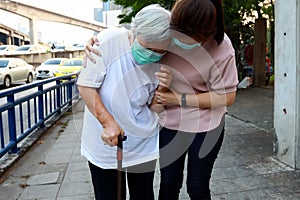 Tired senior woman wearing hygienic mask walk outdoor on street sidewalk in city,feel sick,vertigo,nauseous,allergy to dust, photo