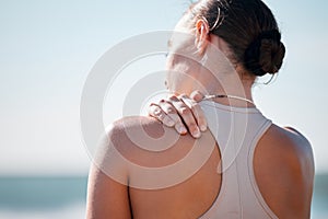 Tired, shoulder pain and fitness with woman at beach with mockup for yoga, workout and training. Burnout, injury and