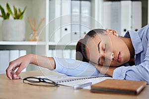 Tired, sleep and woman in business on her table feeling burnout and overworked while sleeping in her office. Nap