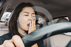 Tired sleepy Asian woman yawning during driving car