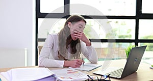 Tired sleepy beautiful woman yawns while working at office desk with laptop