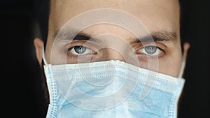 Tired sleepy man in a medical mask looks at the camera. Quarantine, epidemic, Covid-19 virus.