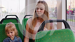 Tired sleepy woman with daughter going home by bus and fall asleep, child kid girl use mobile phone