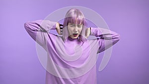 Tired sleepy woman yawns, covers her mouth with hand. Very boring, uninteresting. Violet studio background.