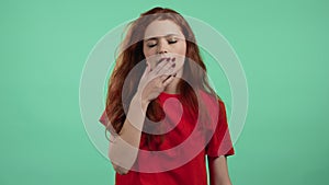 Tired sleepy woman yawns. Girl stretches hands up. Very boring, uninteresting. Green studio background.