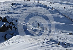 Unavený snowboardista ťahá svoju farebnú dosku za sebou. Tínedžer na vrchole hory zápasí s vetrom. Lyžiarske stredisko v Low