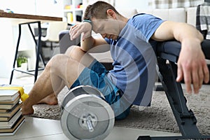 Tired from sports exercises guy sits floor at home