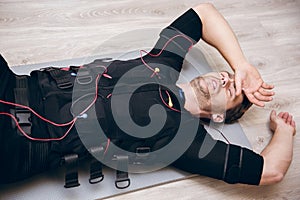 Tired sportsman lying on floor after training with ems