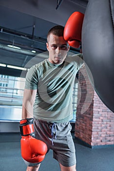 Tired sportsman standing near punching bag after long training