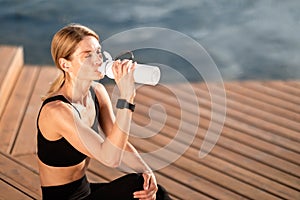 Tired Sporty Middle Aged Woman Drinking Water From Bottle After Training Outdoors