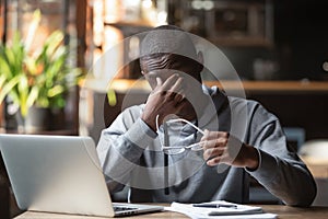 Tired stressed black guy take off glasses feel eye strain