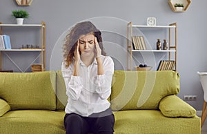 Tired, stressed, nervous, young woman suffering from a headache and holding her temples