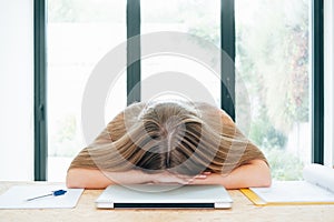 Tired and stressed woman with head down in front of laptop