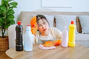 Tired stressed young Asian woman with headache doing spring cleaning chores in her living room at home overworked housekeeping