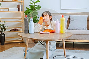 Tired stressed young Asian woman with headache doing spring cleaning chores in her living room at home overworked housekeeping