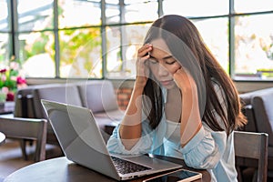 Tired and stressed young Asian woman working with laptop