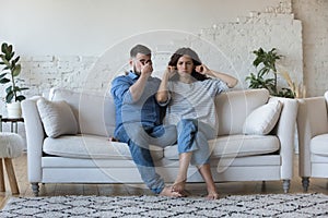 Tired stressed young couple arguing at home, sitting on sofa