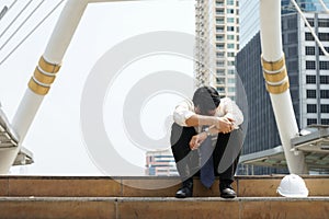 Tired or stressful businessman sitting sadly on stairs after working