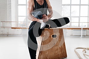 Tired strong man sitting on box at gym