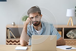 Tired student or employee working with laptop, doing boring job