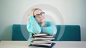 Tired student girl with glasses sleeping on the books in the library