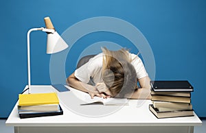 Tired student girl with glasses sleeping on the books in the library. Student studying hard exam and sleeping on books