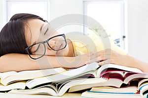 Tired student girl with glasses sleeping on the books