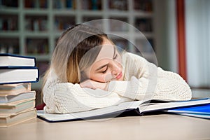 A tired student is studying in the school library.