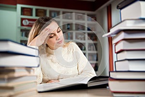 A tired student is studying in the school library.