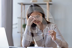 Tired woman rubbing eyes feeling fatigue from glasses computer work photo