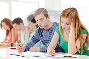 Tired students with textbooks and books at school