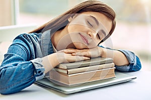 Pleasant girl taking nap on pile of books