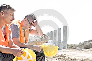 Tired supervisor sitting with colleague at construction site